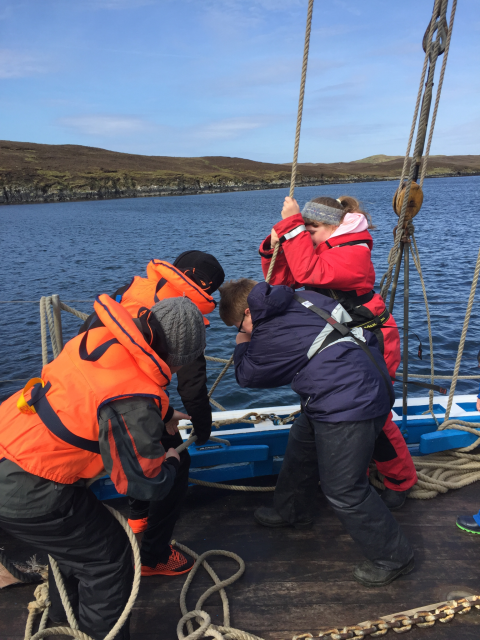 School pupils working together to hoist the sails