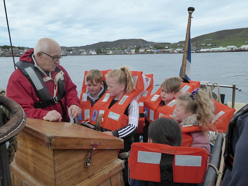 Trustee Brian Wishart showing some of the children the helm of the boat.