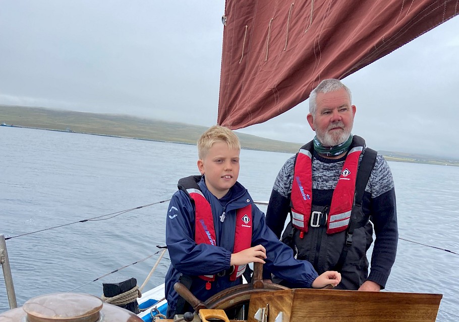 Baltasound pupil at the helm with Swan Trust volunteer crewman Peter Robertson